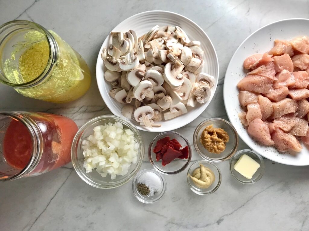 All ingredients prepared in bowls on counter for Brazilian Chicken Stroganoff.  This is an easy 30 minute dinner with a tomato based sauce, cream, and mushrooms all over rice.