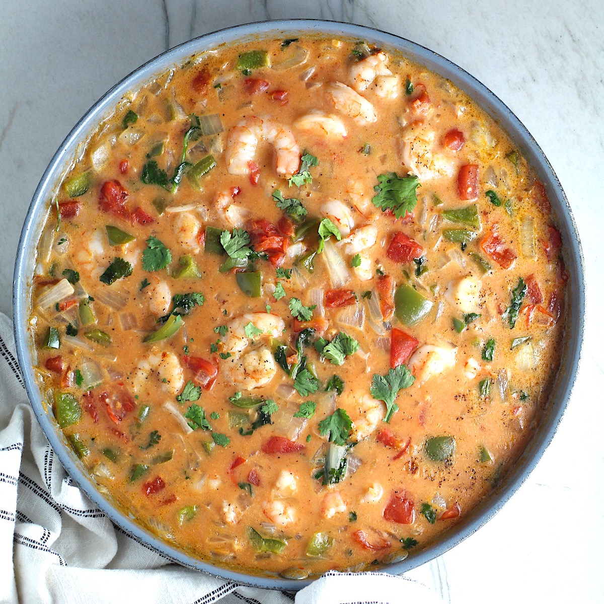 Coconut Shrimp Stew or Moqueca de Camarão, in a pan on counter. It's a delicious traditional dish in Brazil. It's a creamy stew with coconut milk and vegetables.