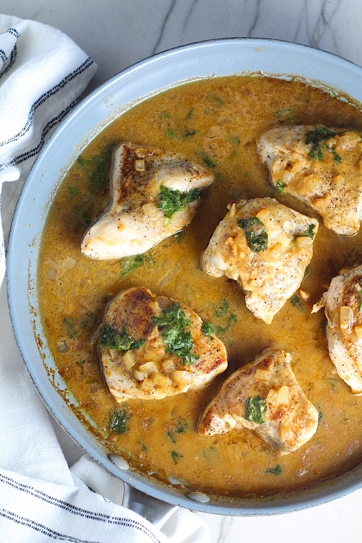 6 pieces of Brazilian Chicken in Peanut Sauce in a pan on counter with dish towel next to it.