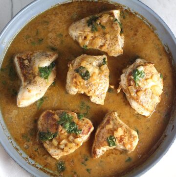 6 pieces of Brazilian Chicken in Peanut Sauce in a pan on counter with dish towel next to it.
