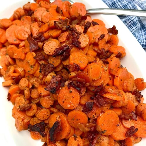 Carrot Bacon recipe on white serving platter with spoon in upper right corner and towel on table.