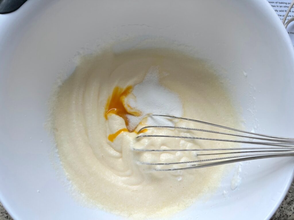 Whisk in bowl about to mix in egg yolk and sugar into batter for Brazilian Coconut Cake.