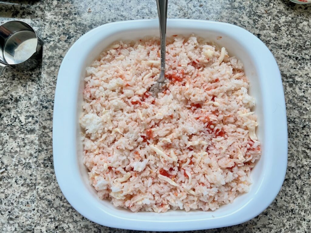 Cooked rice, tomatoes, and cheese mixed together in a casserole dish for Baked Rice with Cheese and Tomatoes.