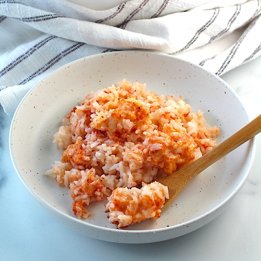 Spoon in bowl of Baked Rice with Cheese and Tomatoes.