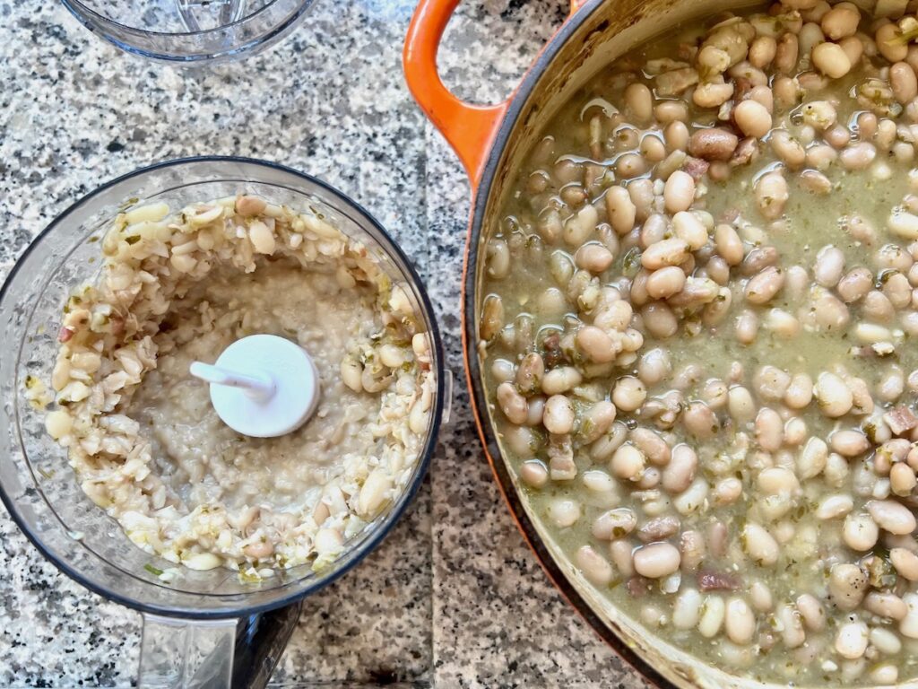 Pot of cooked carioca beans on the right and food processor on the left with some of the beans pureed.