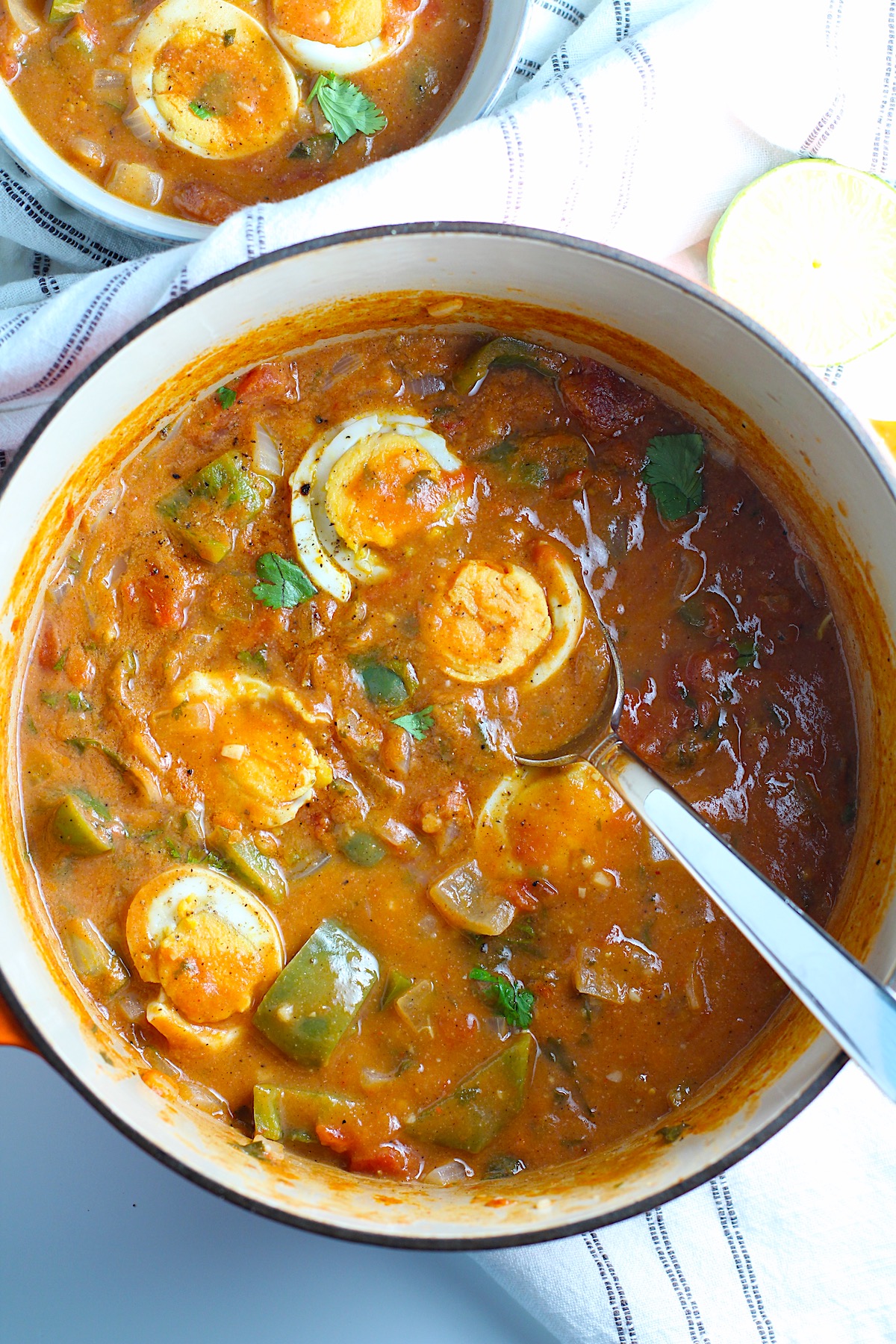 Moqueca de Ovos in a dutch oven pot with sliced hard boiled eggs sitting on top. This is a vegetarian version of a traditional stew in Brazil, where hard boiled eggs replace the seafood.