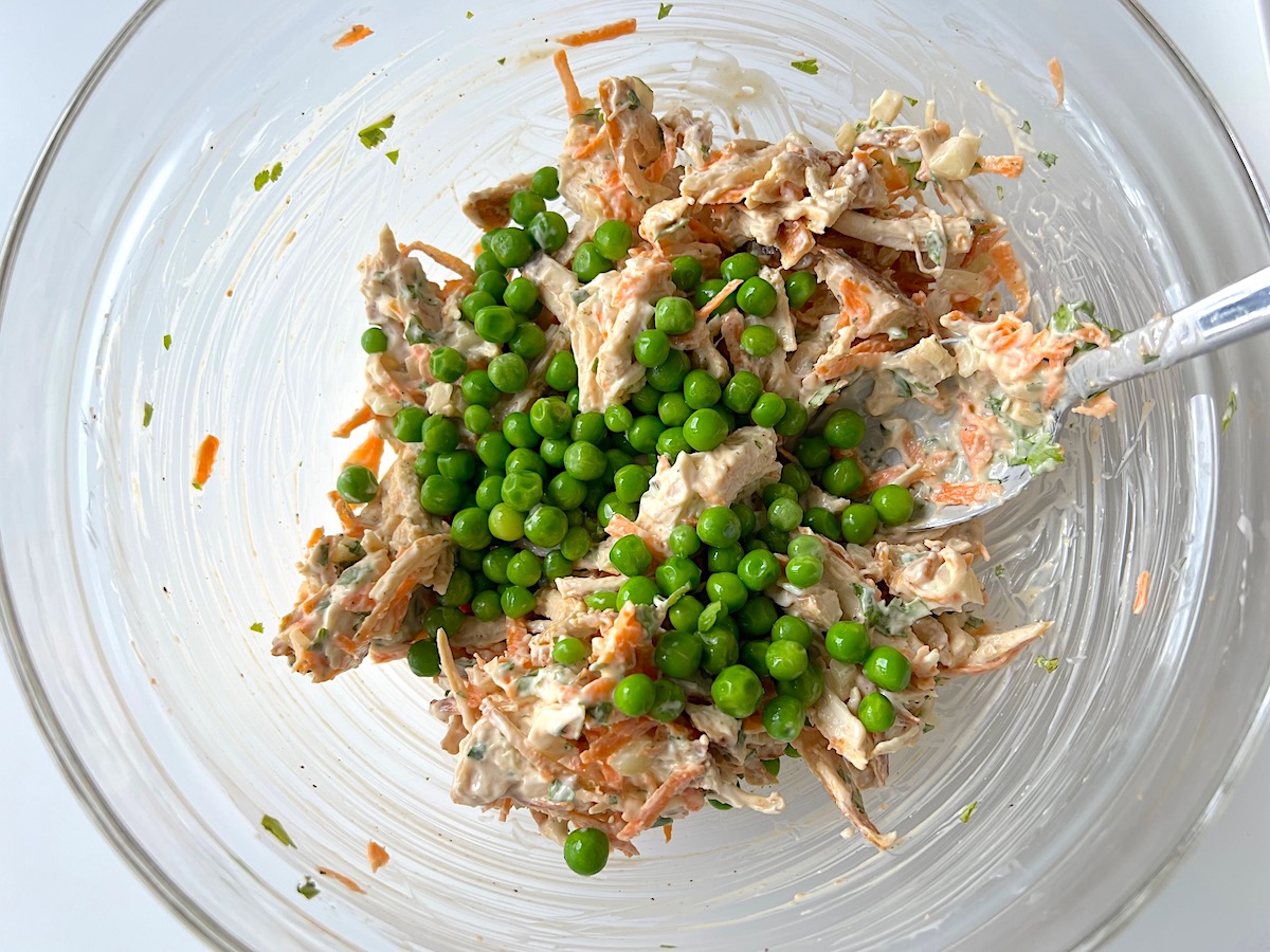 Peas added on top of Brazilian Chicken Salad in a bowl.