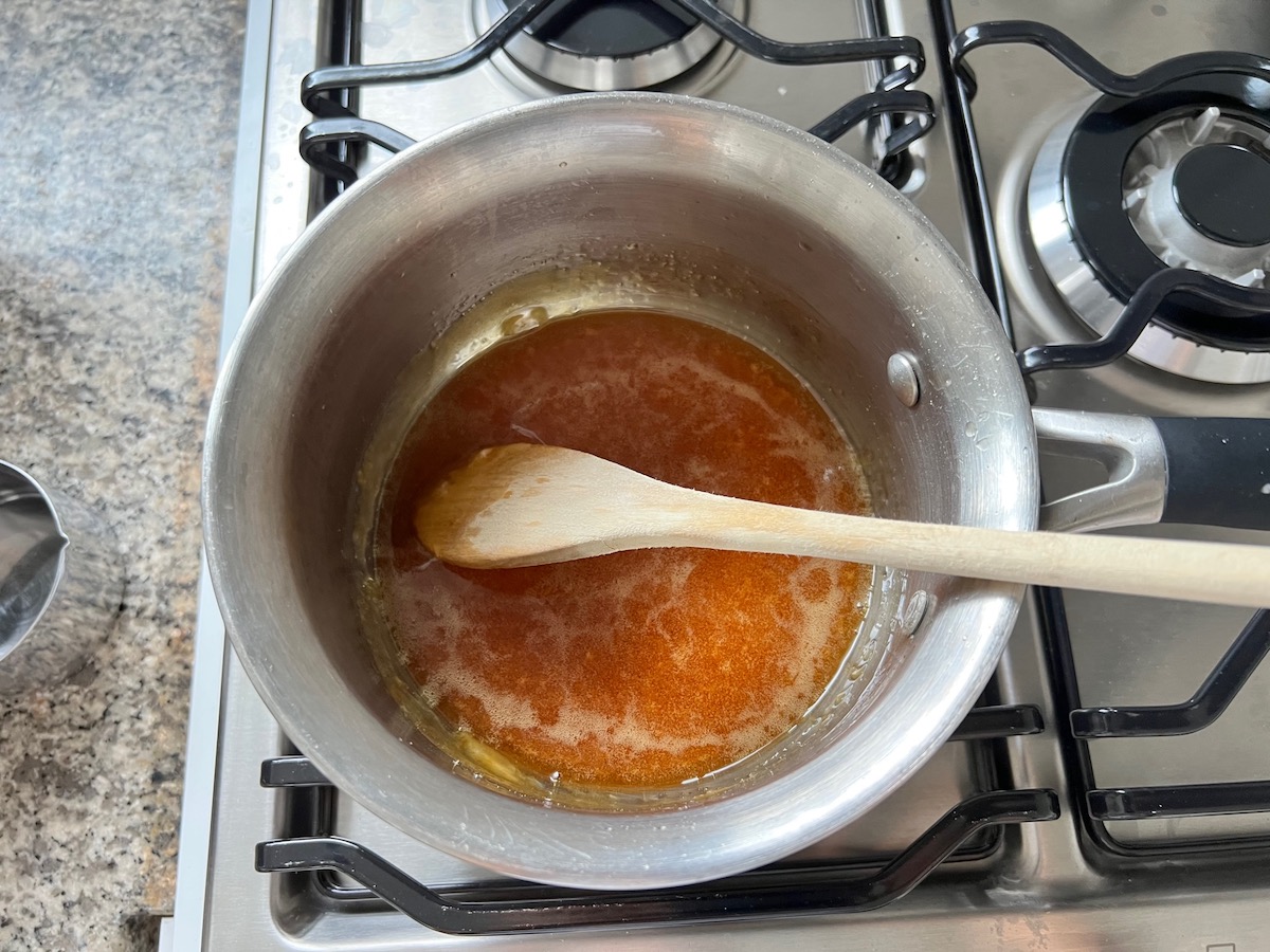 Water added to amber-colored melted sugar to make caramel sauce in a pot for Brazilian Flan Recipe, or Pudim.