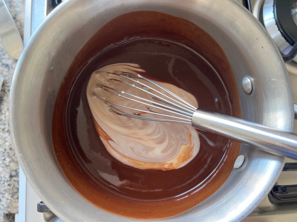 Melted butter and chocolate being mixed with sweetened condensed milk in a pot for Brigadeiro Brazilian Cake.