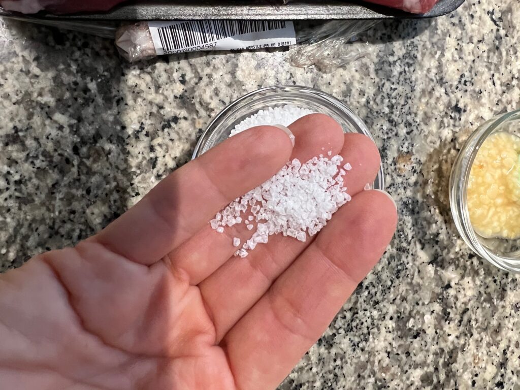 Hand holding coarse salt for Beef with Garlic Sauce.