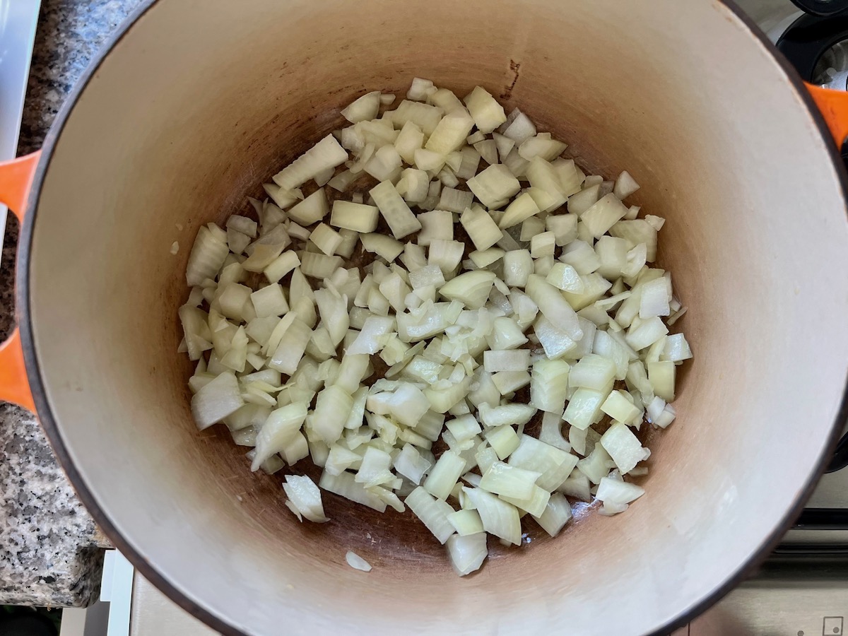 Raw diced onions in pot to cook for Chicken Kale Soup thickened with pureed potatoes (Caldo Verde com Frango).