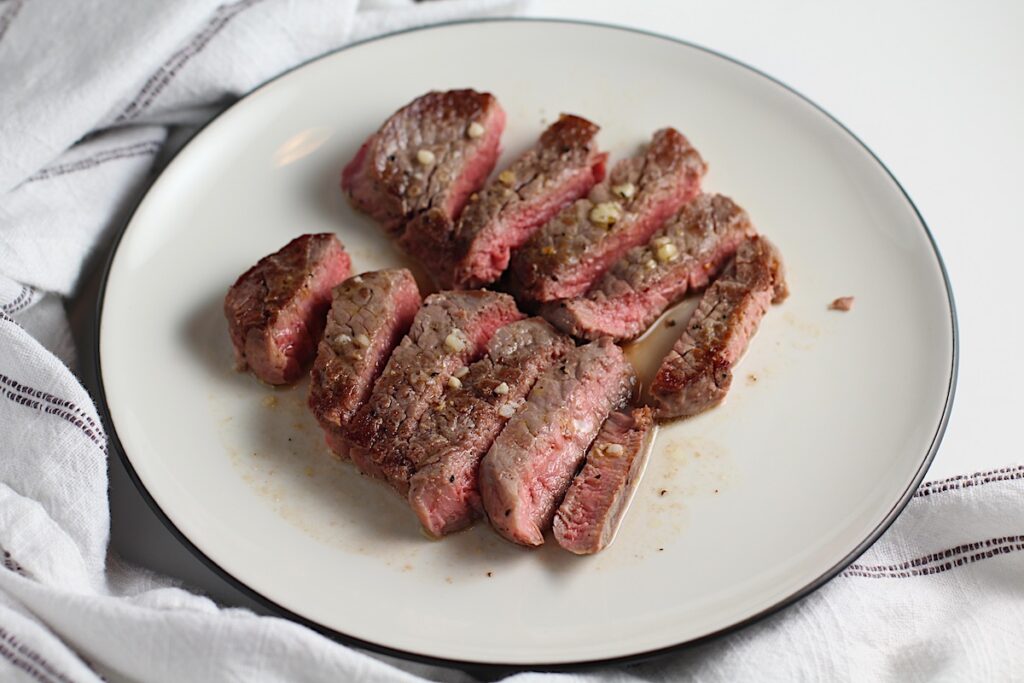 Sliced Filet of beef with garlic sauce on a plate.