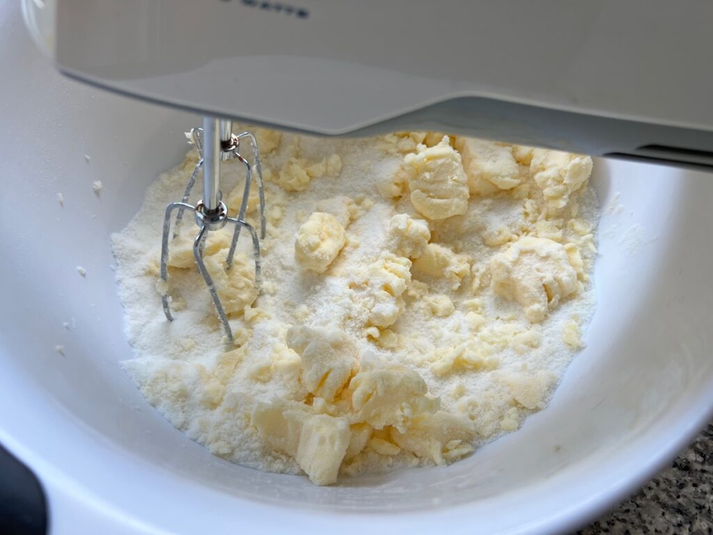 Hand mixer mixing butter and sugar in a bowl for Cake with Lime recipe.