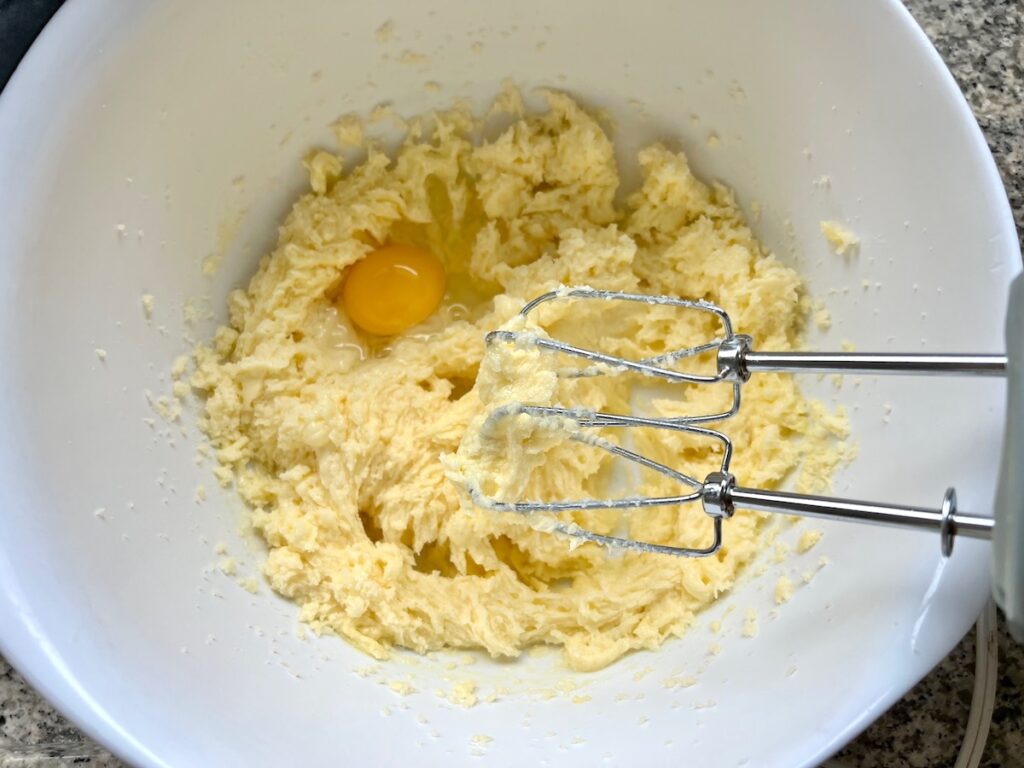 Butter and sugar creamed in a bowl with hand mixer pulled out and 1 egg added for Orange Bundt Cake recipe.