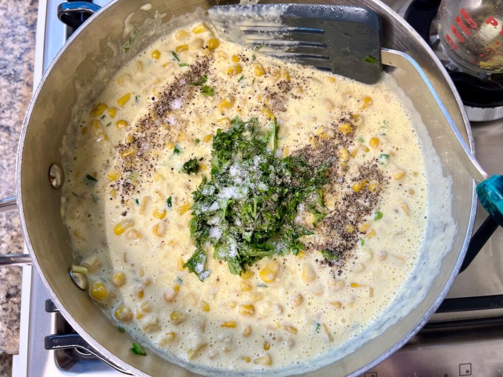 Corn and cream cheese puree plus salt, pepper, and cilantro added to pot with corn kernels and scallions for Corn Casserole Recipe with Cream Cheese.