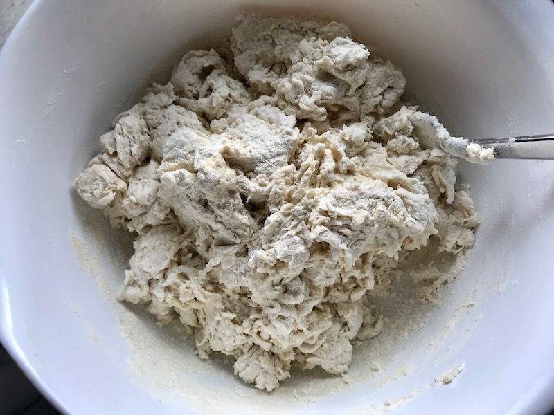 Flour being mixed into water and yeast in a bowl for Brazilian Pizza dough.