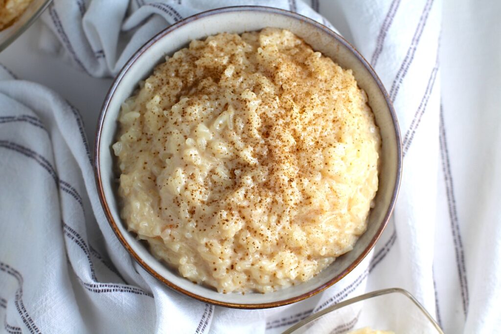 Rice Pudding with condensed milk in a bowl with cinnamon sprinkled on top.