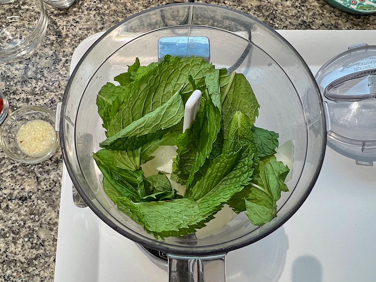 Raw onion and fresh mint leaves in food processor for Kibe Mediterranean Ground Beef Kabab recipe.