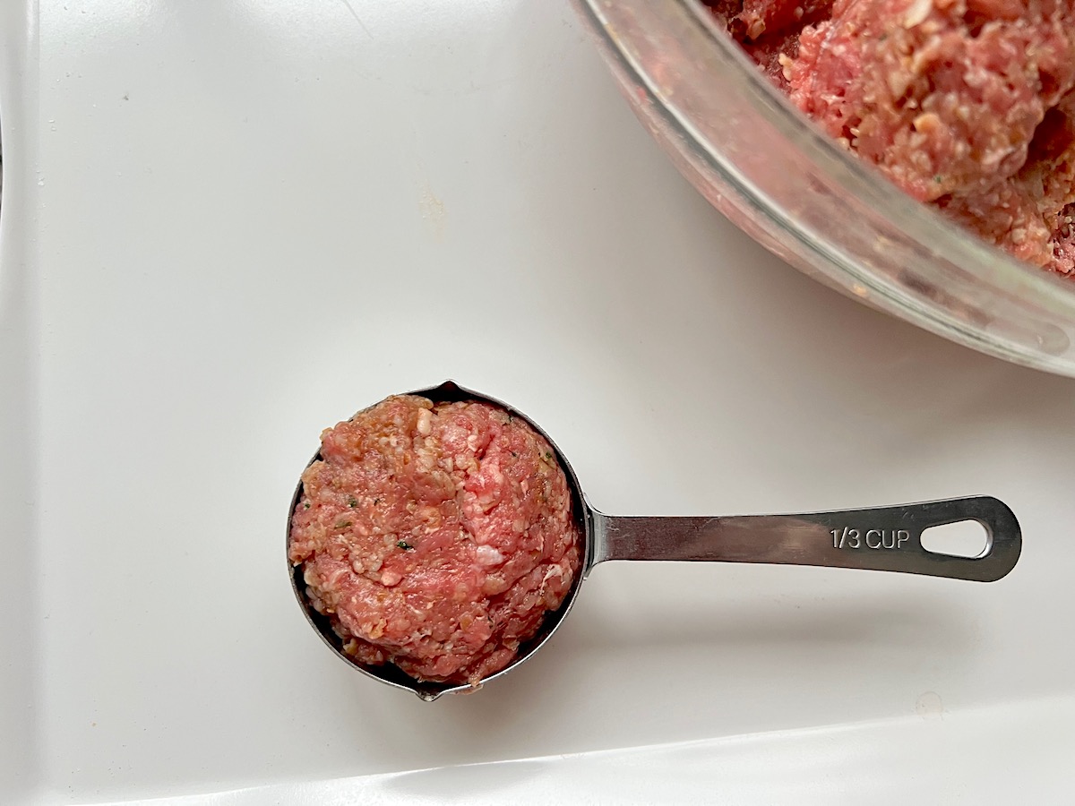 Ground beef mixture scooped up into a ⅓ cup metal measuring cup for Kibe Mediterranean Ground Beef Kabab recipe.