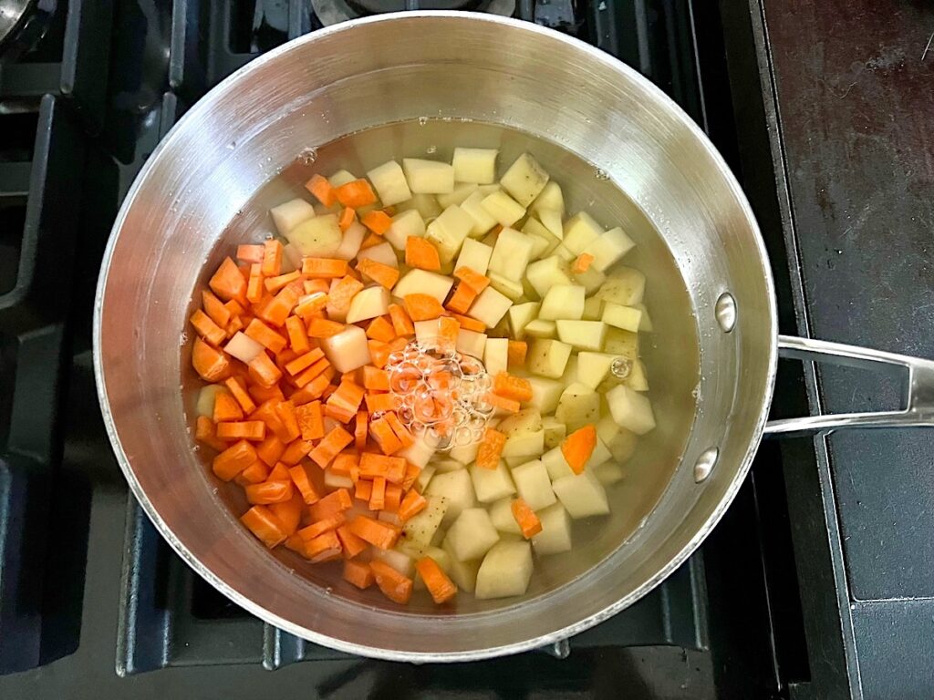 Raw diced carrots and potatoes in a pot with water to be boiled before adding to the filling for the Ham and Leek Pie.