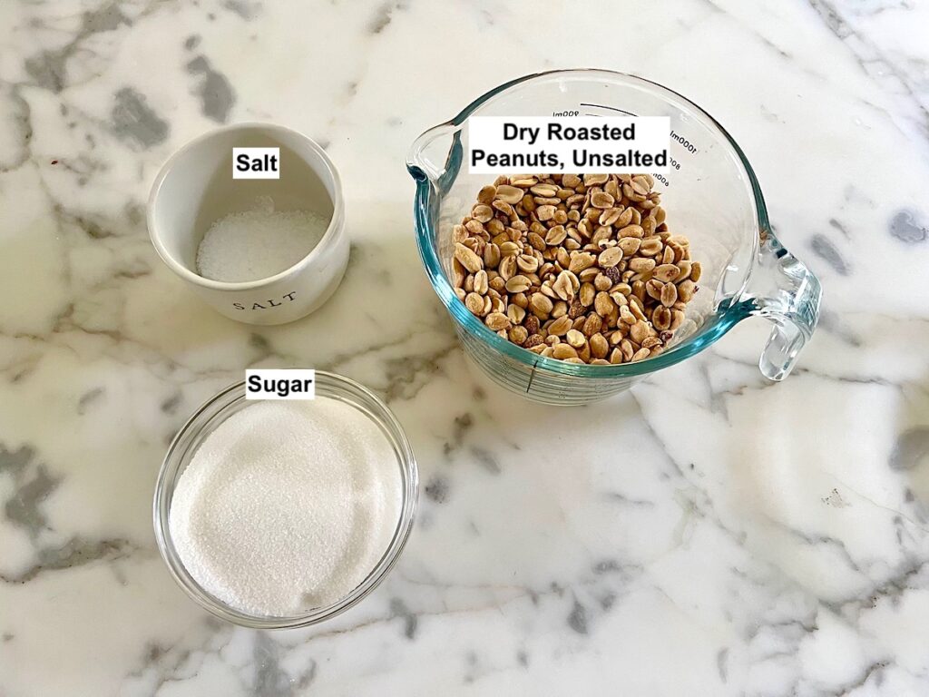 Ingredients for Brazilian Peanut Candy recipe (peanuts, sugar, and salt) measured out into bowls on counter.