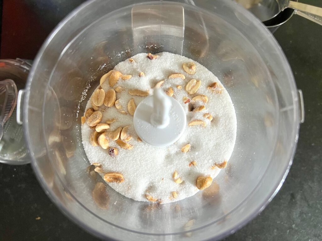 Roasted peanuts, granulated sugar, and salt in a food processor before blending for Brazilian Peanut Candy recipe (Pacoca).